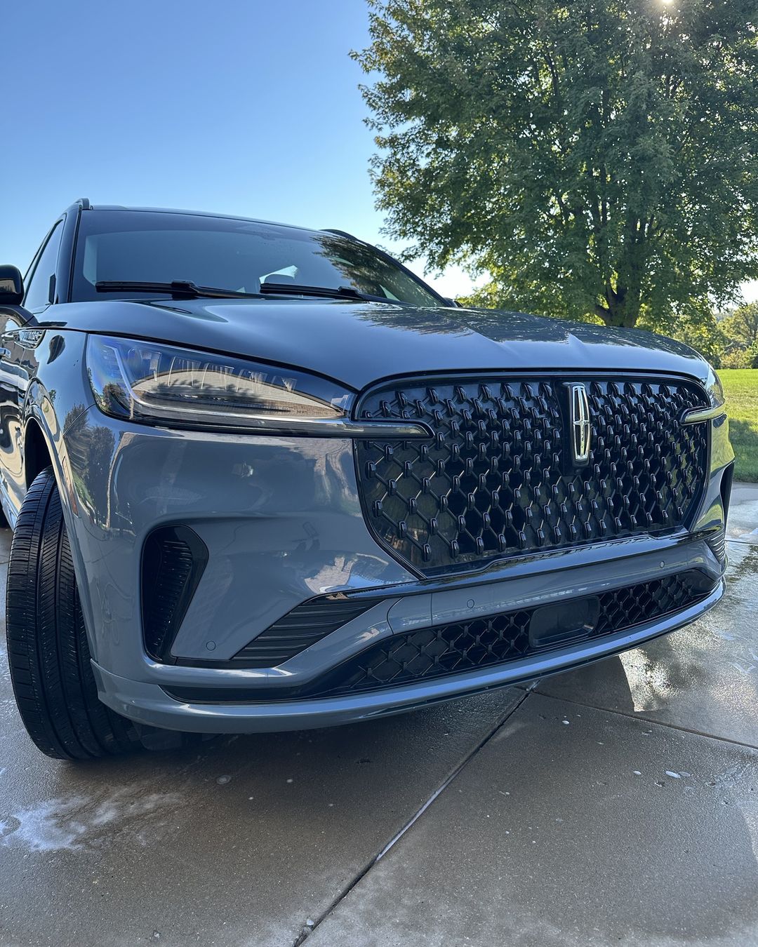 The same Lincoln after the wash, with deep glossy paint reflecting the trees