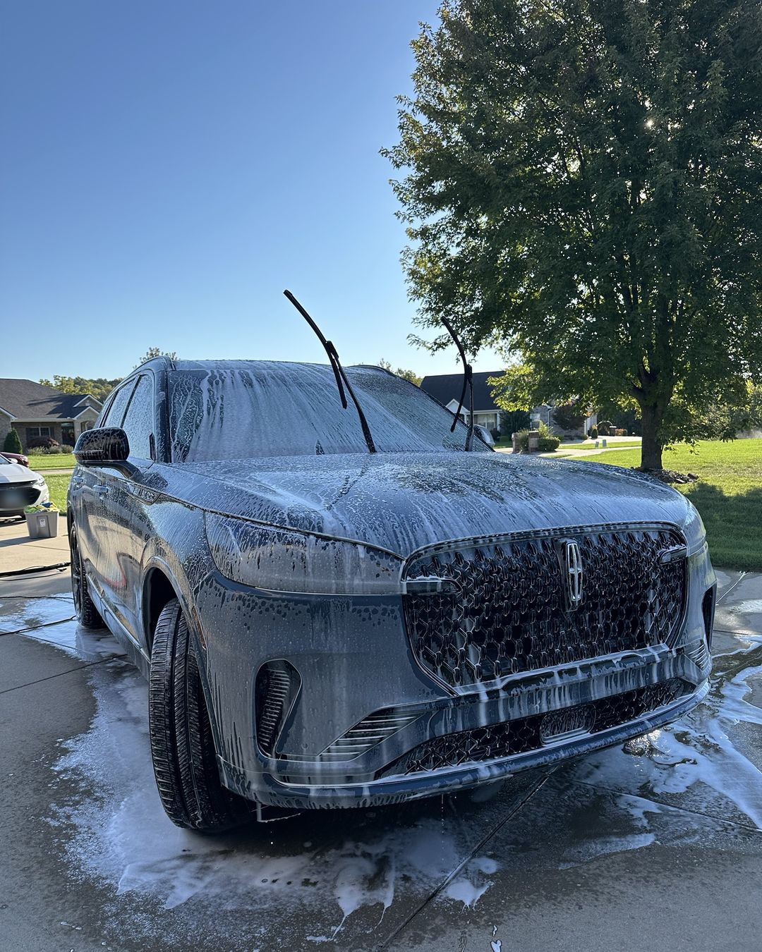 Gray Lincoln SUV covered in thick snow foam in a driveway
